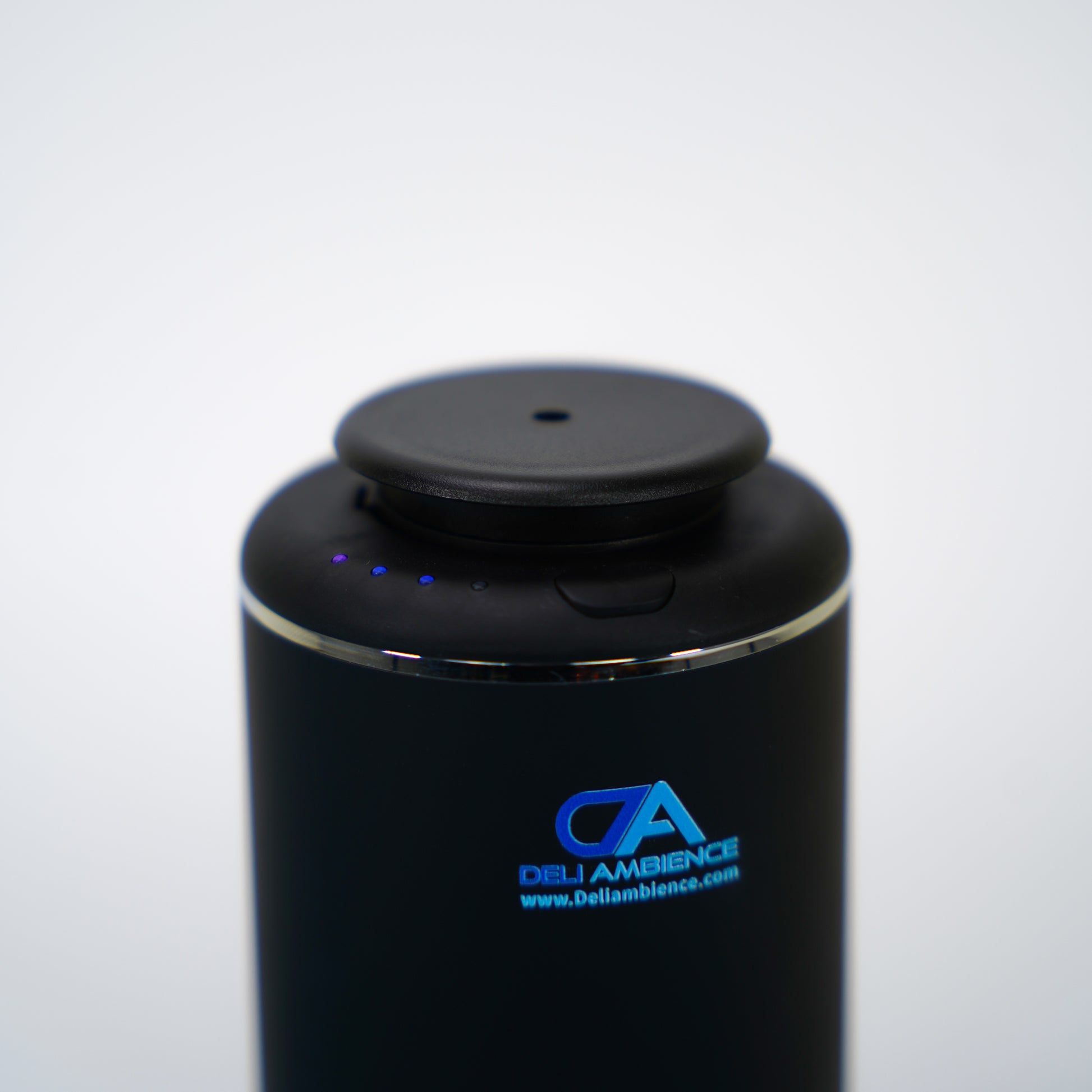 The Venus Compact Oil Diffuser USB-C Power is a cylindrical black electronic device with an LED indicator and the "Del Ambience" logo, perfect for small rooms and featuring a convenient USB-C charge.