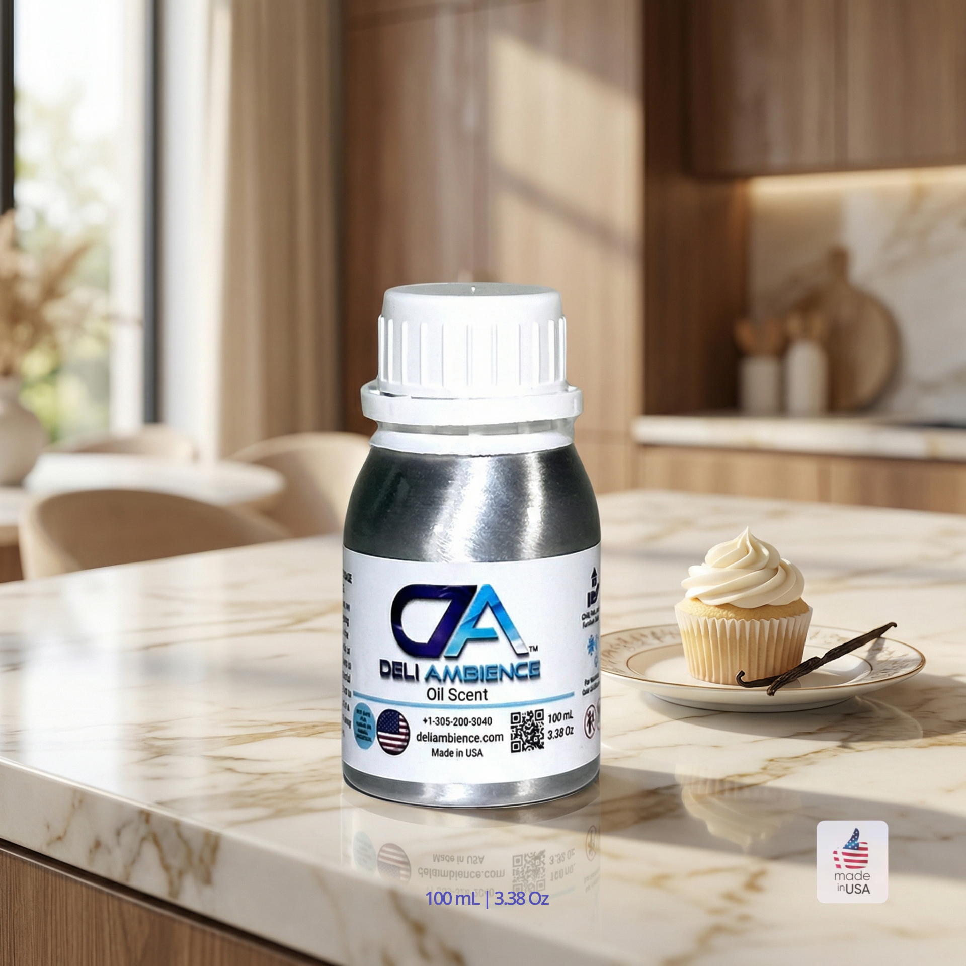 A silver bottle labeled "Vanilla Buttercream Oil Scent" rests on a marble countertop beside a cupcake with creamy vanilla buttercream in a modern kitchen setting.