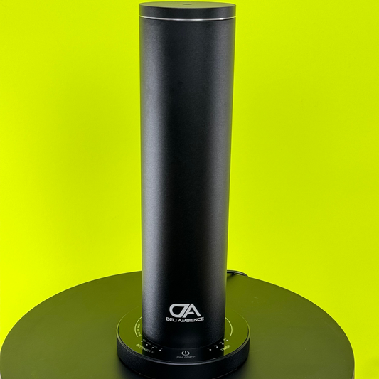 A DA Mini Tower Scent Diffuser sitting on top of a green background.