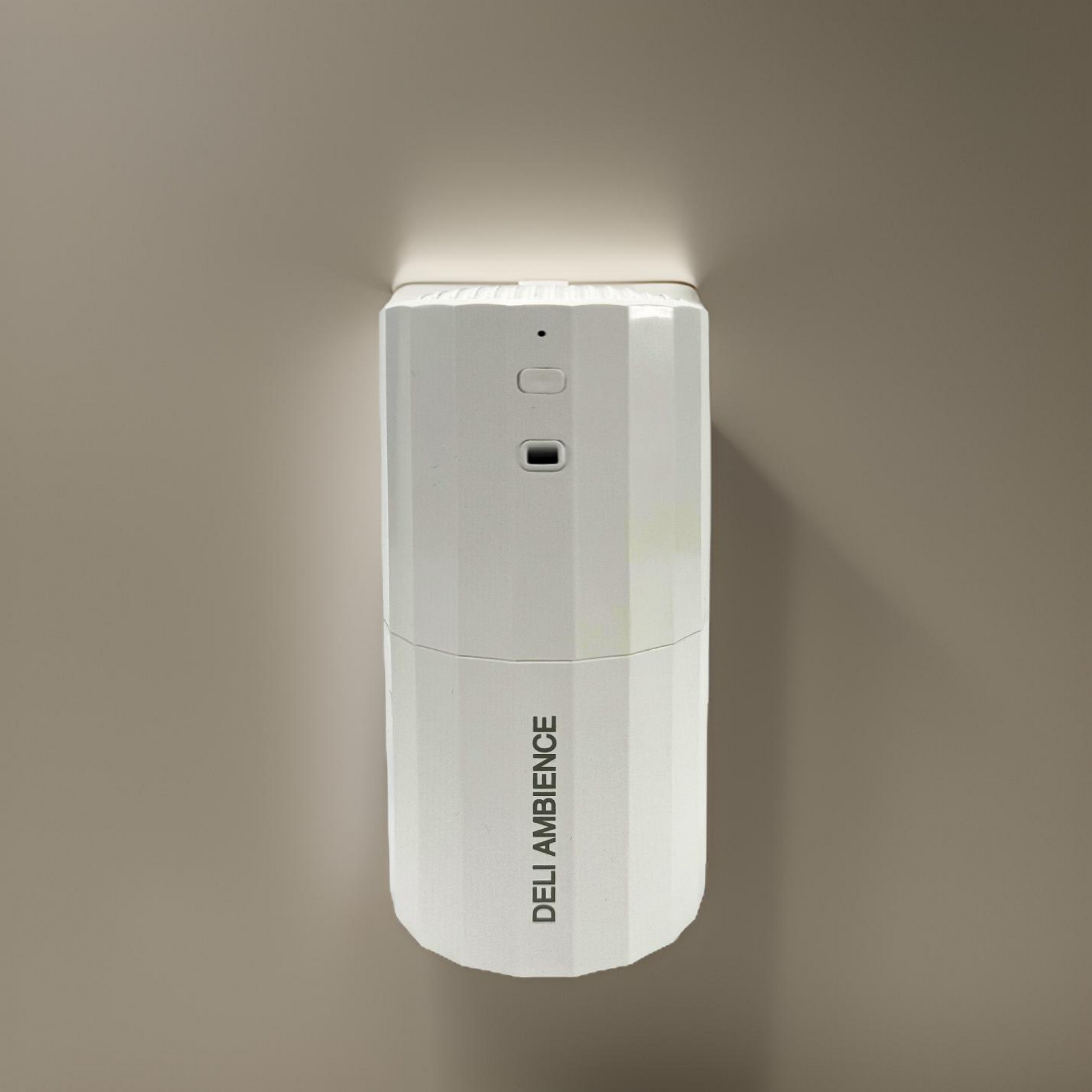 A white wall-mounted air freshener with the label "Deli Ambience 'DA Plug In' Waterless Scent Diffuser" emits a soft light from the top, doubling as a sleek waterless scent diffuser.