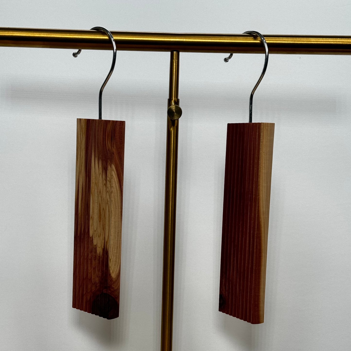 Two Scented Cedar Wood Hangups with Hook for Closets, made of moth-repellent scented cedar wood, on a metal clothing rail against a white background.