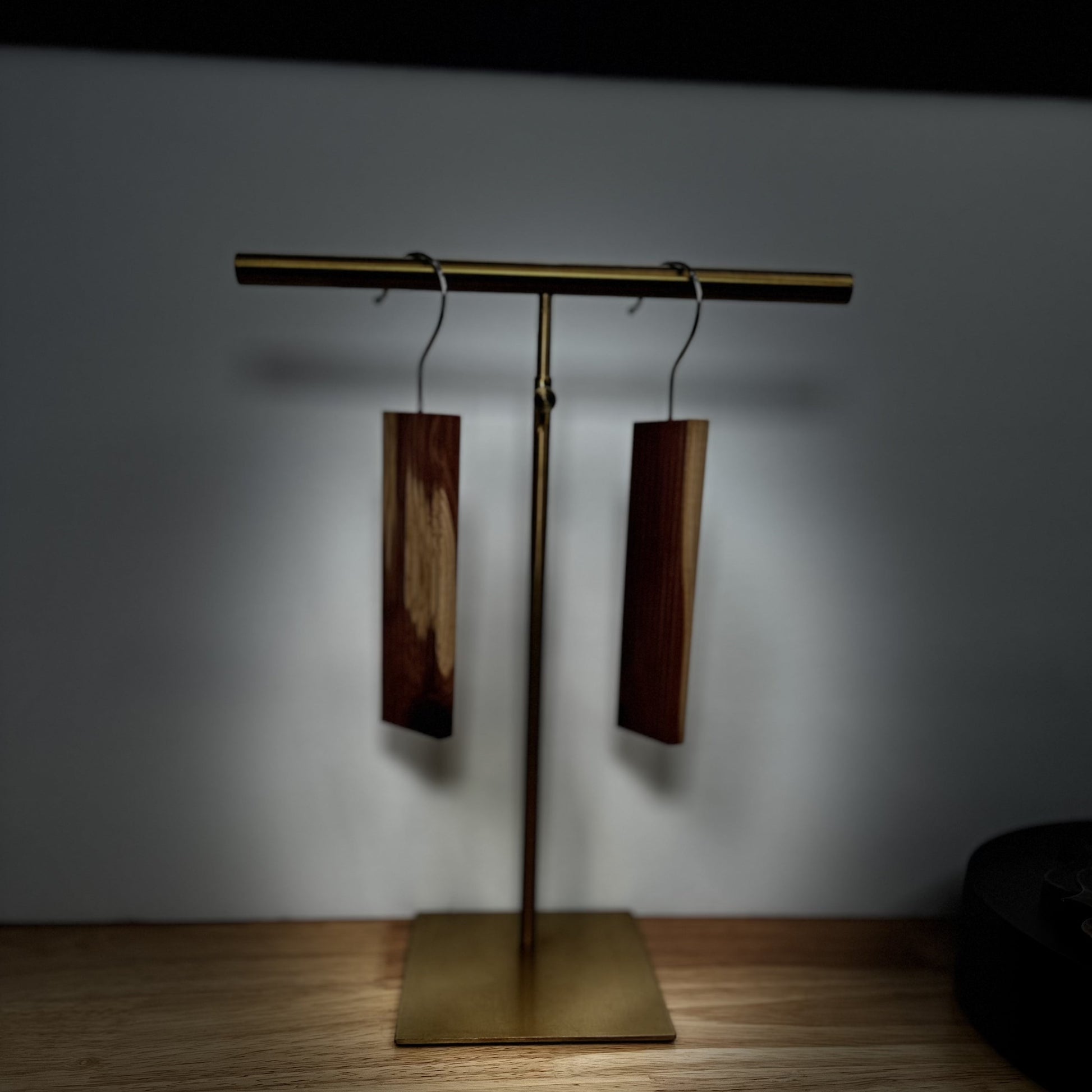 A desk lamp illuminating two wooden headphones on a stand, near Scented Cedar Wood Hangups with Hook for Closets.
