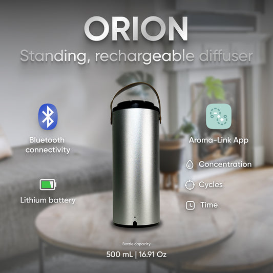 The Orion Oil Scent Diffuser Portable, with its sleek silver aluminum casing, sits elegantly on a table. It features icons indicating Bluetooth connectivity, control via the Aroma-Link App, and a durable rechargeable lithium battery. With a 500 mL capacity, it complements the home setting in the background.