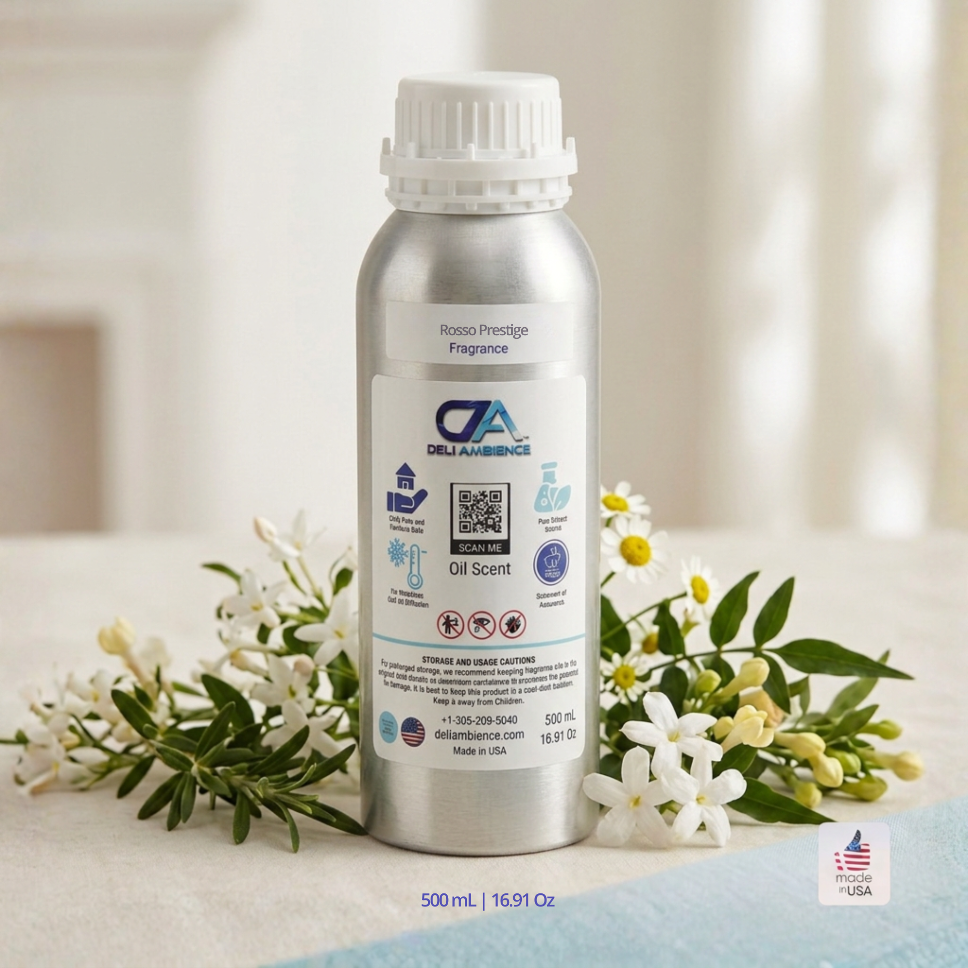A 500 ml aluminum bottle of Rosso Prestige Oil Scent sits on a table among white and yellow flowers, releasing a refined aroma highlighted by citrus and floral perfume notes.